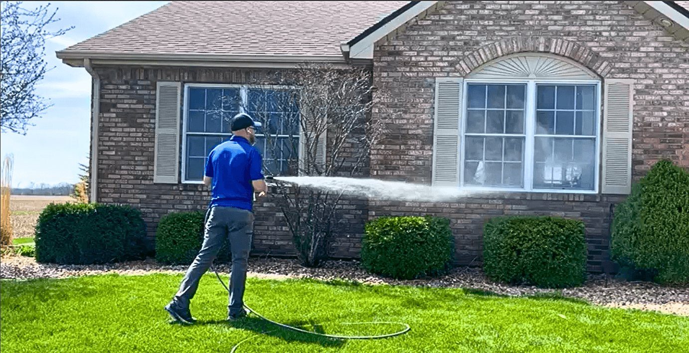 Crew member working a wand along the brick and siding of an Indiana home