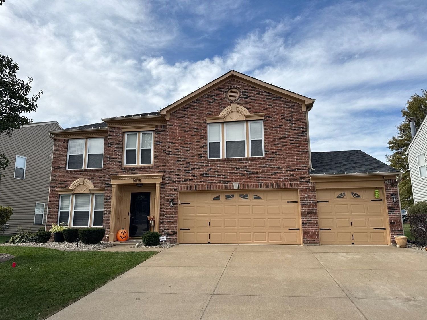 Brick and siding two story Fishers home with a cleaned drive