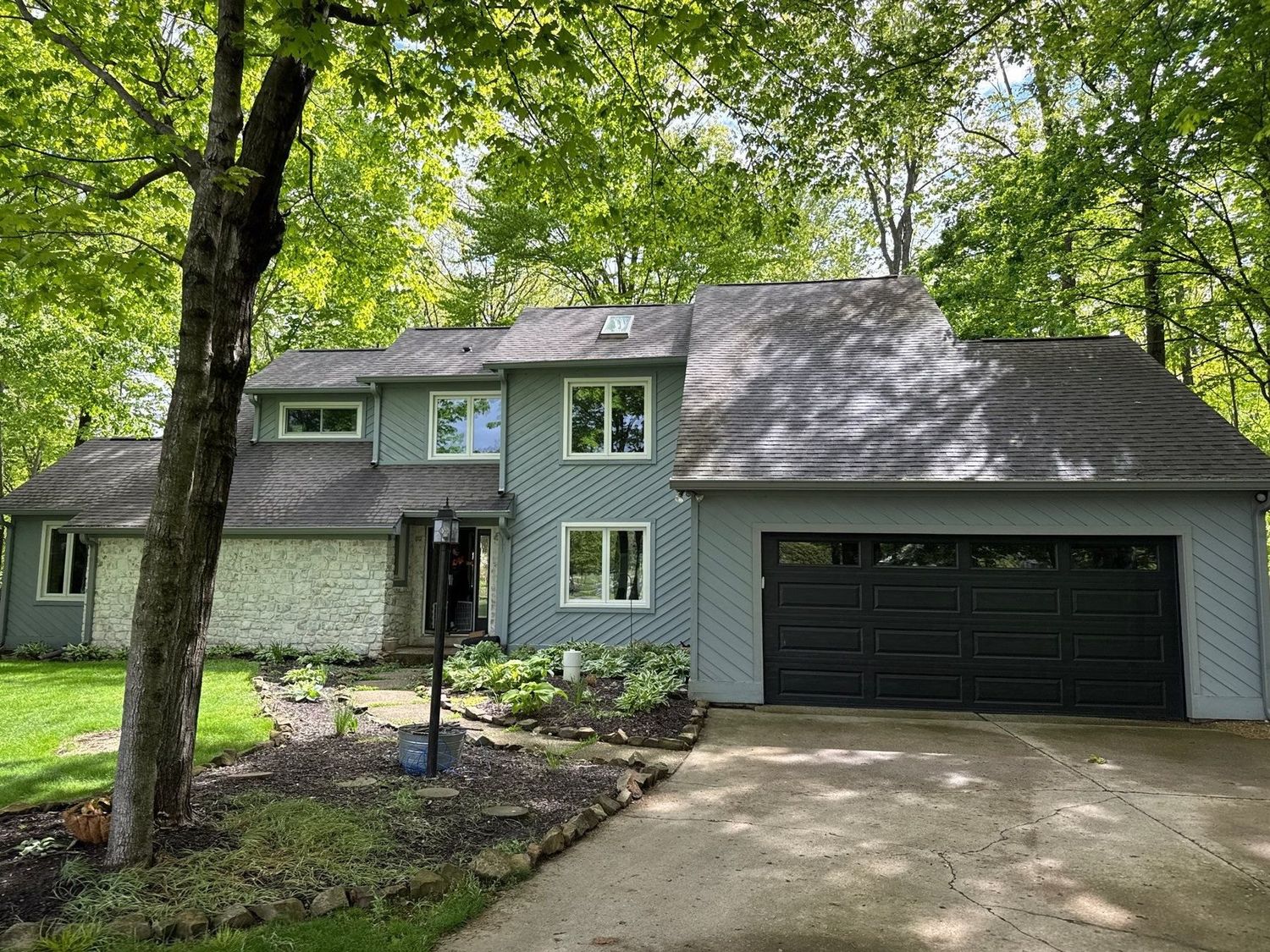 Noblesville home in green siding with a cleaned drive and garage doors
