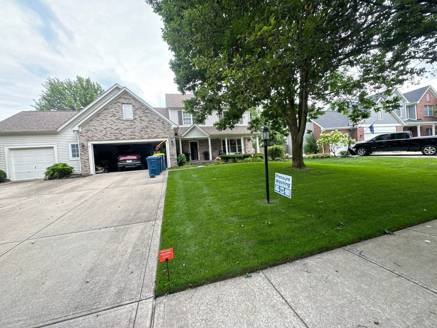 Cleaned concrete driveway at a Noblesville home with the crew sign in the yard
