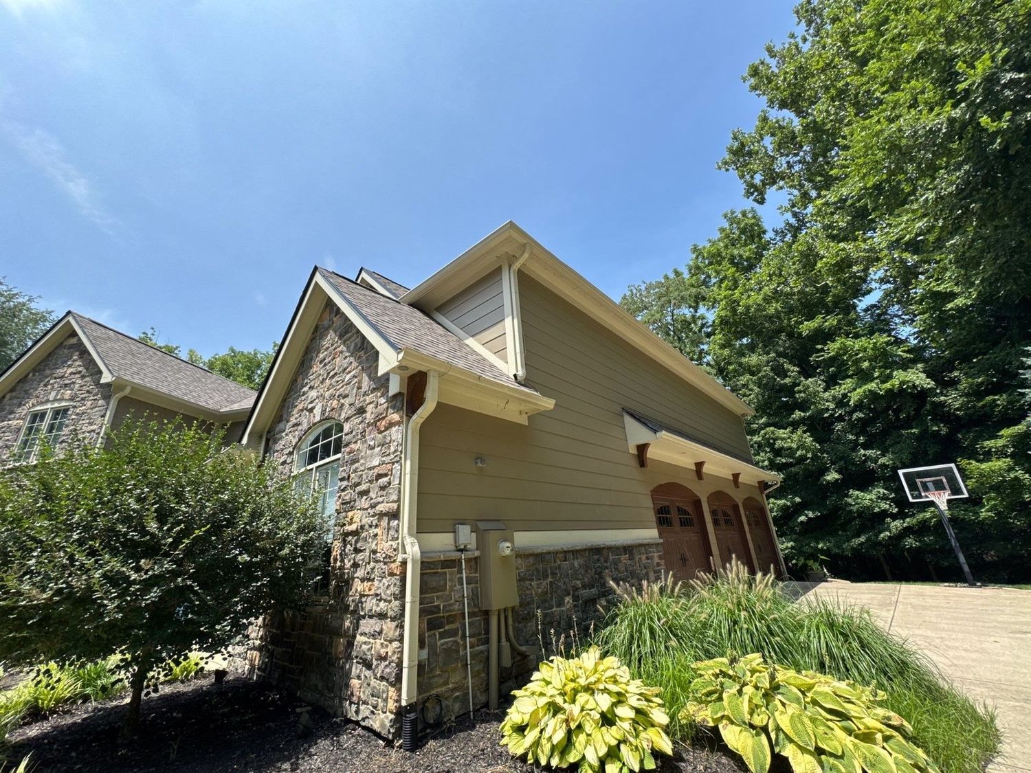 Fishers home in stone and siding with deep planted beds after cleaning