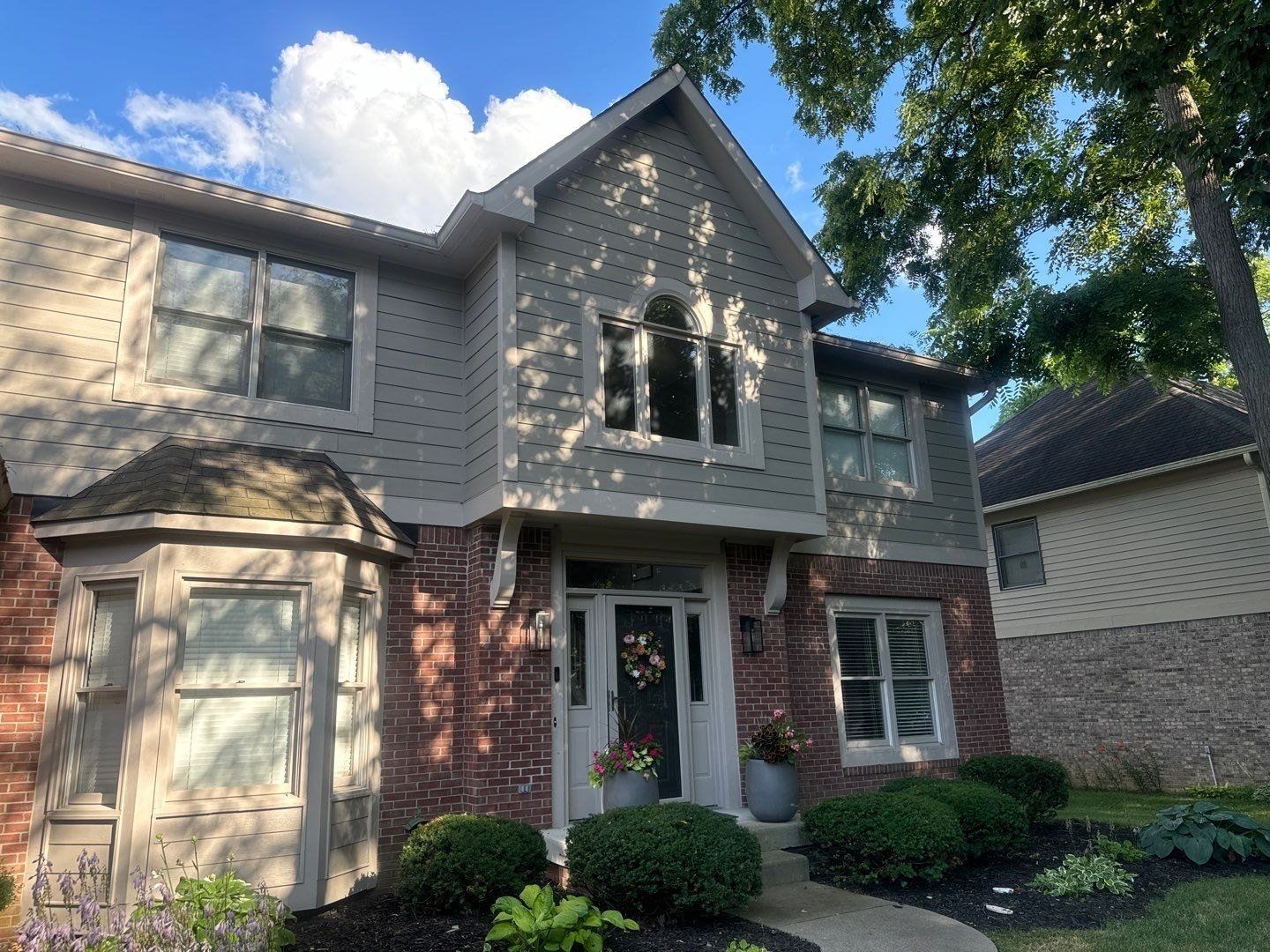 Gray and brick Fishers home with planted beds after a house wash
