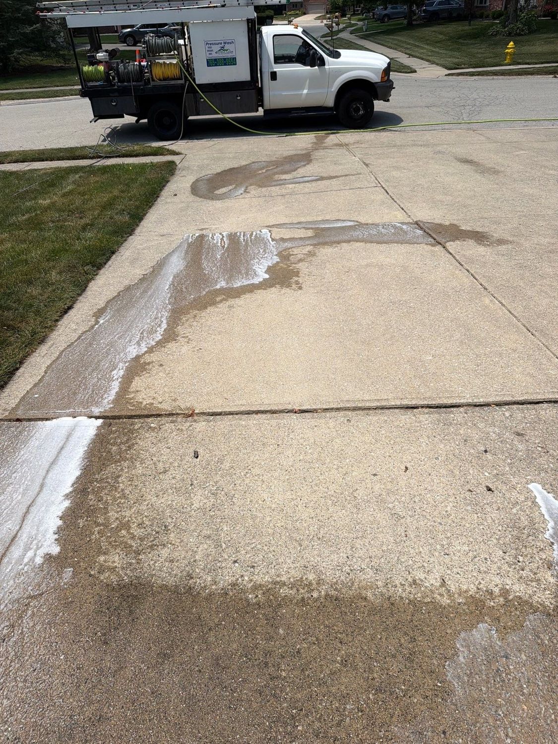 Carmel driveway cleaned across half its width, the cleaned strip bright against the rest