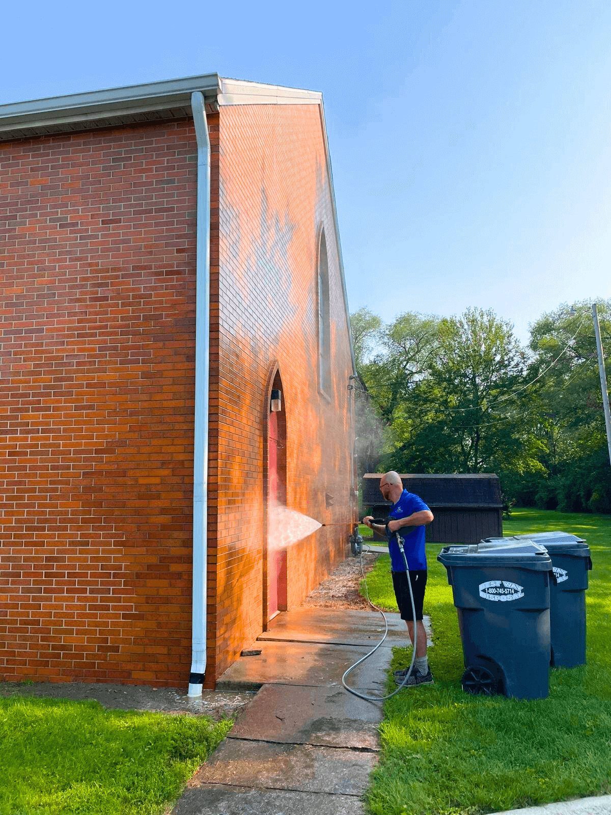 Crew member washing the brick wall of an Indiana commercial building