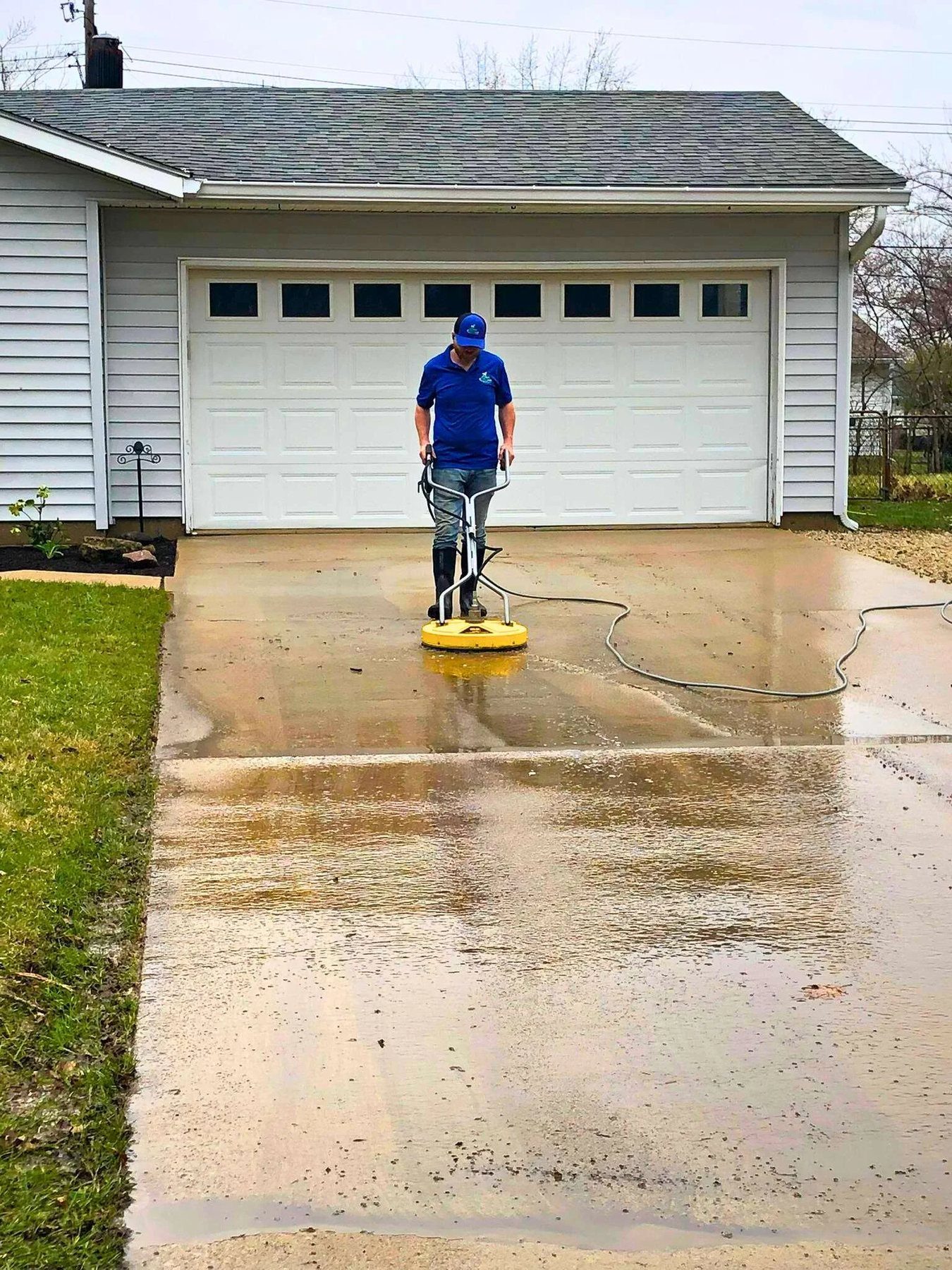 Rotary surface cleaner taking years of grime off a concrete driveway